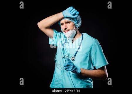 Foto von Kerl doc professionelle unglücklich Hand auf der Stirn gestresst bekam infizierte Patienten tragen Maske Uniform Anzug Kleid Kunststoff Gesichtsbrille chirurgisch Stockfoto