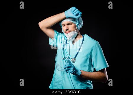 Foto von Kerl doc professionelle unglücklich Hand auf Stirn ermüdend Operation überwältigt tragen Maske Uniform Anzug Kleid Kunststoff Gesichtsbrille chirurgisch Stockfoto