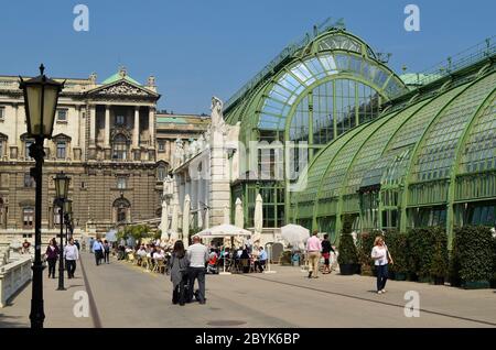 Wien, Österreich - 24. April 2011: Unbekannte Menschen gehen und erholen sich im öffentlichen Burggarten mit neu renoviertem Palmenhaus-Café mit Hofbu Stockfoto