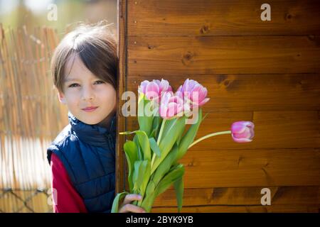 Kind, Junge mit rosa Tulpen , versteckt sich hinter ihnen, Muttertag Geschenk Konzept Stockfoto