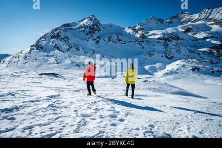 Zwei Wanderer stehen auf dem Gipfel über dem Tal in den Bergen. Wunderschöne Schweizer Alpen Winterlandschaft an einem hellen sonnigen Tag. Winter im Freien Stockfoto