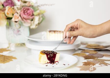 Hand mit Gabel Essen baskischen gebrannten Käsekuchen mit gemischten Beerensauce. Stockfoto