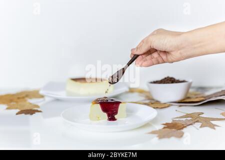 Frau gießt Kakao Nibs und Beeren Sauce auf Scheibe baskischen verbrannt Käsekuchen. Stockfoto