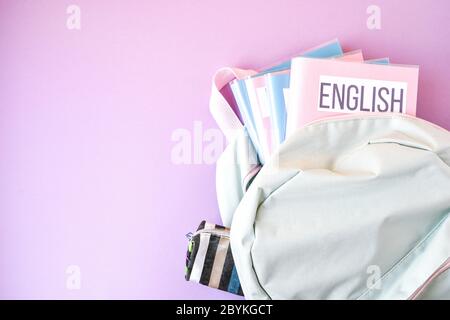 Flache Lage Zusammensetzung mit Rucksack und Schulbedarf und Themenbücher auf farbigem Hintergrund. Kopierraum Stockfoto