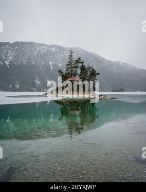 Schöner Wintertag am Eibsee bei grainau an der zugspitze, Spiegelung der Insel Braxeninsel im Winter Stockfoto