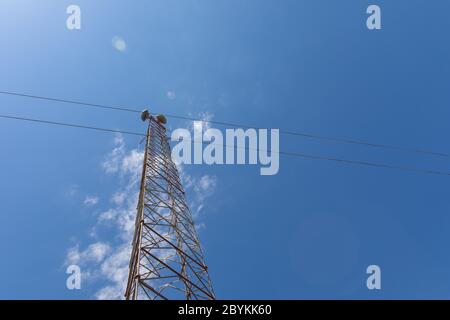 Extrem hoher Telekommunikationsturm von unten mit Mikrowellenantennen, Silhouetten vor einem schönen blauen Himmel mit spärlichen Wolken, Kopie Spa Stockfoto