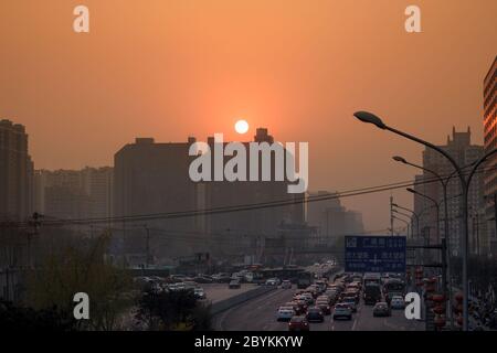 Peking / China - Mai 2019 : Sonnenuntergang während eines sehr verschmutzten Tages über der Dawang Road in der Nähe des Hopson One Shopping Mall Stockfoto