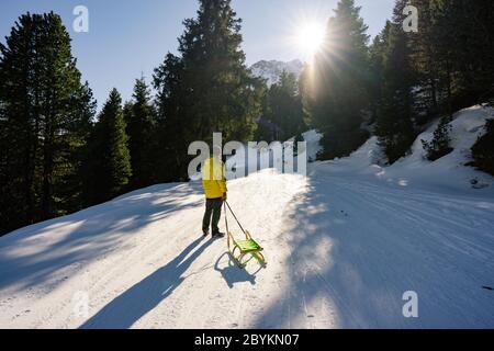 Tourist Mann im Urlaub Winterreise Spaß an der Ankunft der europäischen Winter mit ihrem Schlitten. Wanderer auf Schneeberg. Stockfoto