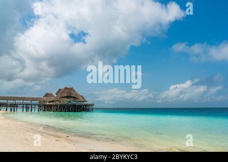Tropischer weißer Strand mit einem traditionellen Gebäude über dem Wasser, Sansibar Island Tansania. Schöner Himmel, kopieren Sie Platz für Text Stockfoto