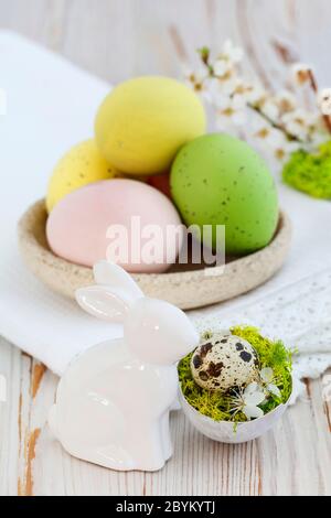 Ostertischdeko mit bunten Eiern und Keramik rabit Figur. Festliche Einrichtung Stockfoto