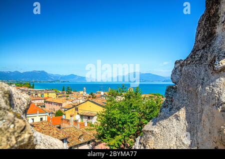 Blick auf das historische Zentrum Desenzano del Garda Altstadt, See und Bergkette durch Merlons von Backstein zerstörte Mauer der mittelalterlichen Burg, blauer Himmel Kopieplatz, Lombardei, Norditalien Stockfoto