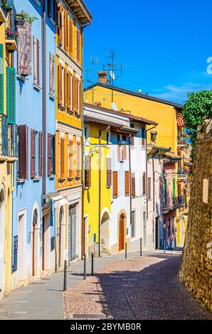 Typische schmale Straße in der Altstadt von Desenzano del Garda Stadt mit Kopfsteinpflaster Straße und traditionellen bunten Gebäuden mit Fensterläden, vertikale Ansicht, Lombardei, Norditalien Stockfoto