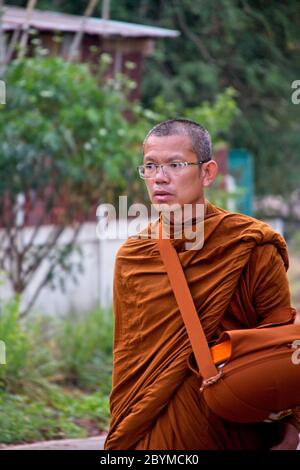 Buddhistische Mönche, die zu Fuß oder in ein Dorf transportiert werden, um Lebensmittelspenden zu sammeln. Stockfoto