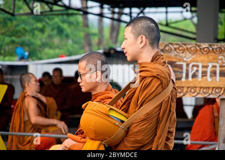 Buddhistische Mönche, die zu Fuß oder in ein Dorf transportiert werden, um Lebensmittelspenden zu sammeln. Stockfoto