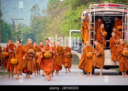 Buddhistische Mönche, die zu Fuß oder in ein Dorf transportiert werden, um Lebensmittelspenden zu sammeln. Stockfoto