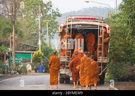 Buddhistische Mönche, die zu Fuß oder in ein Dorf transportiert werden, um Lebensmittelspenden zu sammeln. Stockfoto