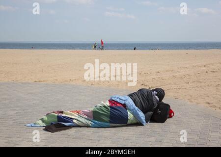 Obdachloser schläft auf einem leeren Coney Island Beach wegen der Covid-19 Pandemie. Brooklyn, New York. Stockfoto