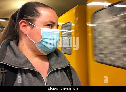 23.04.2020, Berlin, Deutschland - Frau in einer U-Bahn-Station trägt in Zeiten einer Corona-Pandemie Mund- und Nasenprotektor. 00S200423D061CAROEX.JPG [MODELL Stockfoto