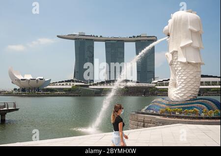 05.05.2020, Singapore, , Singapur - EINE Frau spaziert am Ufer des Singapore River entlang des ansonsten menschenleeren Merlion Parks und trägt einen Mundguar Stockfoto