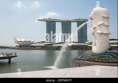 05.05.2020, Singapore, , Singapore - leerer Merlion Park mit Springbrunnen am Ufer des Singapore River und dem Marina Bay Sands Hotel im Hintergrund Stockfoto