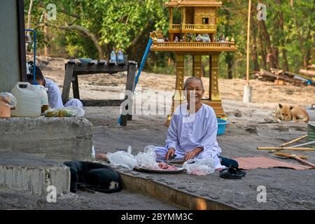 Nonne in weißer Kleidung, die hilft, Nahrung für die buddhistischen Mönche vorzubereiten. Stockfoto