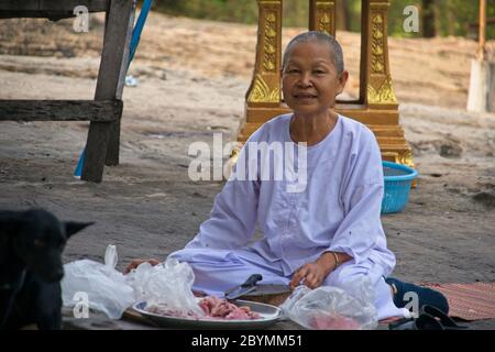 Nonne in weißer Kleidung, die hilft, Nahrung für die buddhistischen Mönche vorzubereiten. Stockfoto