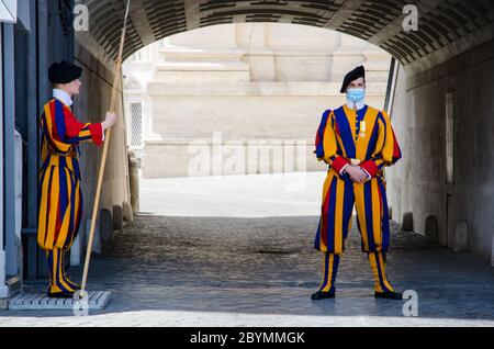 Rom, Italien. Frühjahr 2020. Schweizer Wachen in traditioneller Uniform, die vor dem Wachposten stehen, tragen die Anti-Covid-Maske Stockfoto