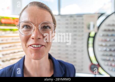 Eine junge attraktive Frau in einem Optikgeschäft versucht sich neue Gläser. Kopierraum Stockfoto