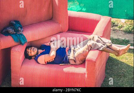 Udaipur, Indien - 10 Feb. 2014 - Indischer Mann schläft und ruht auf Sessel im Freien Stockfoto