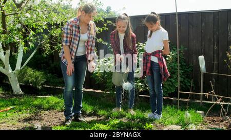 Glückliche Familie im Garten arbeiten und Gemüse gießen Stockfoto