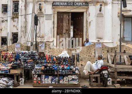 Chennai, Tamil Nadu, Indien - August 2018: Die alte armenische Kirche in Georgetown mit einem älteren Mann, der Schuhe auf dem Bürgersteig draußen verkauft. Stockfoto