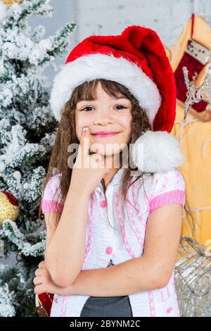 Happy Little girl in santa Hut vor Weihnachtsbaum Stockfoto