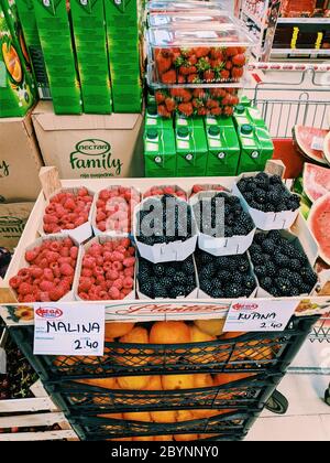 Budva, Montenegro - 10. juni 2020: Kisten mit Himbeeren und Brombeeren stehen auf Kisten mit Orangen im Supermarkt. Stockfoto