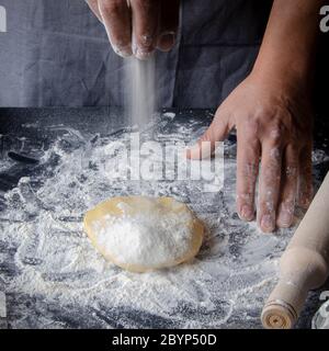 Kochen Sie die Hände Knetmasse, bestreuen Stück Teig mit weißem Weizenmehl Stockfoto