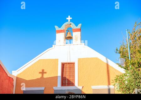 Bunte griechische Kirche gegen einen blauen Himmel mit einem Schatten des Kreuzes auf das Gebäude in Oia, Santorini, Griechenland Stockfoto