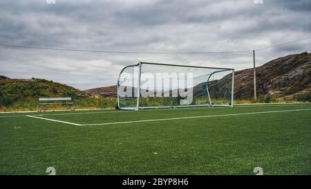 Leeres Trainingstor für klassischen Fotbal auf Grüngras Spielplatz auf Lofoten Inseln umgeben von Felsen und Steinen. Sport in Norwegen, Henningsvaer Stockfoto