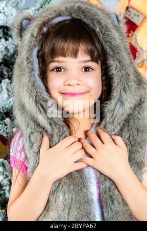 Niedliche kleine glückliche Mädchen posiert in einem Pelzhut. Stockfoto