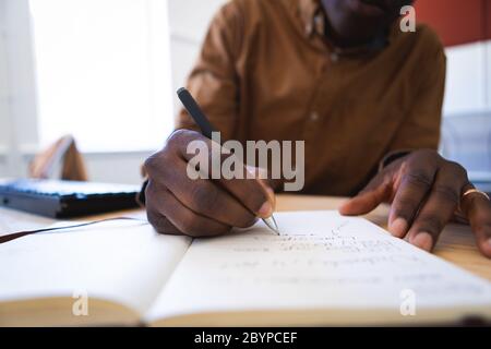 Afroamerikanisch Schreiben auf einem Notizbuch in einem Büro Stockfoto