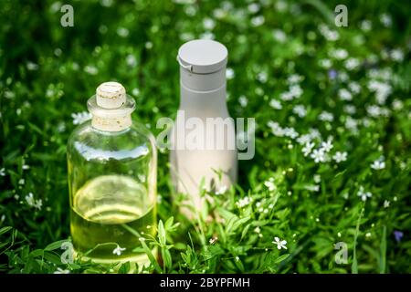 Natürliches Bio-Öl, Serum in der Flasche und Haar Shampoo auf grün grasigen Hintergrund Stockfoto