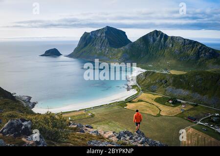 Abenteuerlicher Mann steht auf dem Berg und genießt die schöne Aussicht während eines lebendigen Sonnenuntergangs. Schöne Natur Norwegen Naturlandschaft Stockfoto