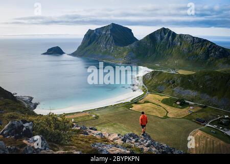 Abenteuerlicher Mann steht auf dem Berg und genießt die schöne Aussicht während eines lebendigen Sonnenuntergangs. Schöne Natur Norwegen Naturlandschaft Stockfoto