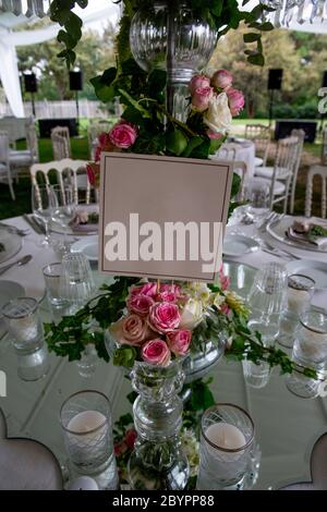Tischnummer steht für einen luxuriösen Hochzeitsempfang im Freien auf dem Land; weiße rustikale tiffany-Stühle, Tischblumen-Arrangements, Kristallcent Stockfoto