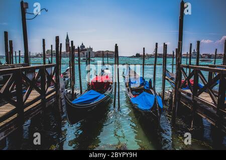 Zwei traditionelle Canale Grande Gondeln, die am Pier festgemacht sind, die Kirche und die Insel San Giorgio Maggiore im Hintergrund, Venedig, Italien Stockfoto