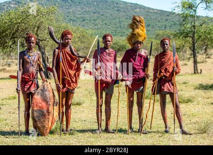 Eine Gruppe junger Masai-Krieger steht in der Savanne in traditioneller Kleidung mit Speeren. Tansania, Ostafrika, 12. August 2018. Stockfoto