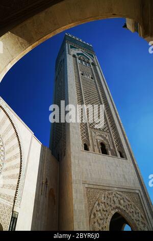 Das 60-stöckige Minarett der Hassan II. Moschee (umgangssprachlich als "Casablanca Hajj" bekannt) ist im Bogen des Gehwegs in Casablanca, M, eingerahmt Stockfoto