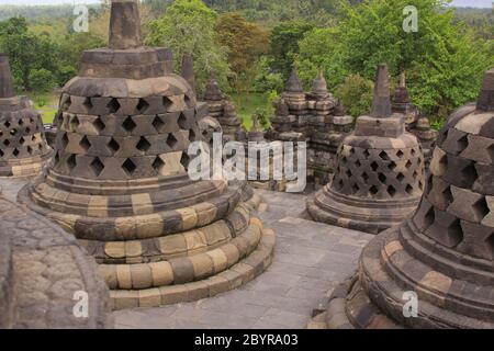 Stupas Anordnung auf Treppen am Borobudur buddhistischen Tempel. Candi Borobudur ist der größte buddhistische Tempel der Welt. Berge und Wolken bei Sonnenuntergang Stockfoto