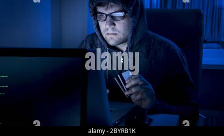Porträt von Hacker mit Kreditkarten arbeiten am Computer in der Nacht Stockfoto