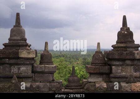 Architektur Gebäude Detail Borobudur Tempel und Wolken. Kleine Stupas an der Wand des Candi Borobudur, dem größten buddhistischen Tempel der Welt. Stockfoto