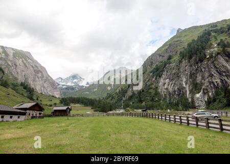 Grünes Tal mit Tiroler Häusern auf dem Hintergrund von alpinen Gipfeln im Nebel. Wanderreise Outdoor-Konzept, Reise in die Berge, Kals am Grossgl Stockfoto