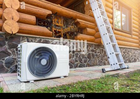 Neue moderne Klimaanlage Klimaanlage externe Kompressor-Einheit für die Installation oder den Ersatz in der Nähe der Wand von Holz-Log Wohn-Landhaus vormontiert Stockfoto